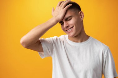Sad teenager boy failed, touching face against yellow background