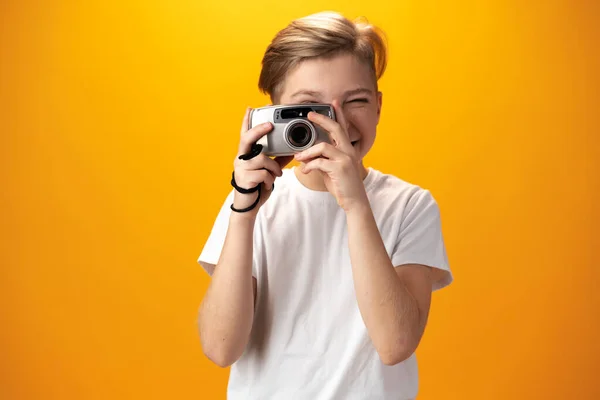 Menino com uma câmera velha em um fundo amarelo — Fotografia de Stock