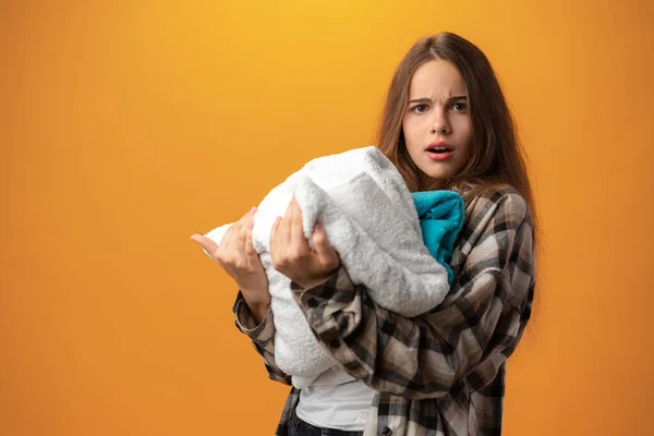 Adolescente chica sosteniendo sucio ropa contra amarillo fondo — Foto de Stock