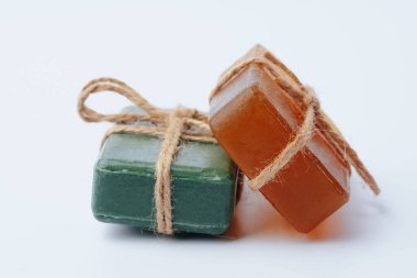 Beyaz üzerine izole edilmiş kurdeleyle bağlanmış doğal sabun çubukları.