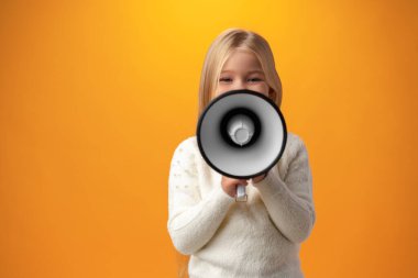 Child girl using megaphone against yellow background