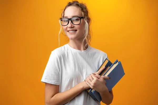 Söt söt flicka med böcker på gul bakgrund — Stockfoto