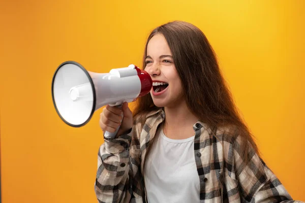 Menina criança usando megafone contra fundo amarelo — Fotografia de Stock