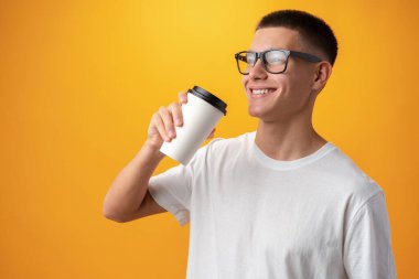 Teen boy with glasses and coffee to go on yellow