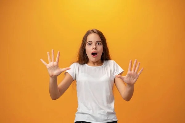 Налякана молода дівчина-підліток показує стоп жест на жовтому тлі — стокове фото