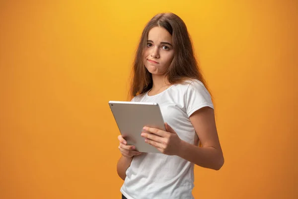 Menina adolescente bonita usando tablet digital sobre fundo estúdio amarelo — Fotografia de Stock