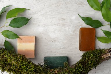 Doğal el yapımı sabun ve gri arka planda bitkiler.