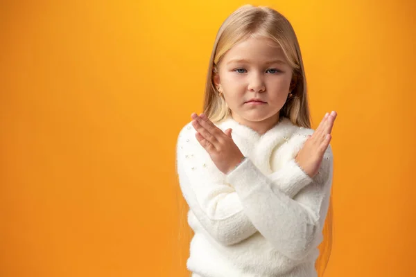 Portrait of little child girl with crossed arms against yellow background — Stock Fotó