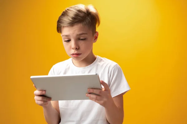 Little boy playing with digital tablet against yellow background — Fotografia de Stock