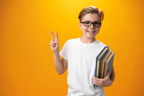 Mały uczeń trzyma książkę na żółtym tle — Zdjęcie stockowe