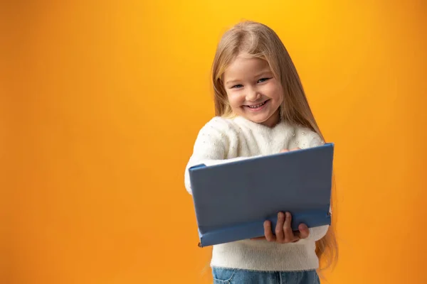 Portret małej uroczej dziewczynki robiącej notatki na żółtym tle — Zdjęcie stockowe
