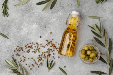 Gri zemin üzerinde zeytin yağı olan cam şişe.