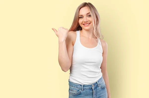 Wanita muda tersenyum menunjuk untuk menyalin ruang yang terisolasi pada latar belakang warna — Stok Foto