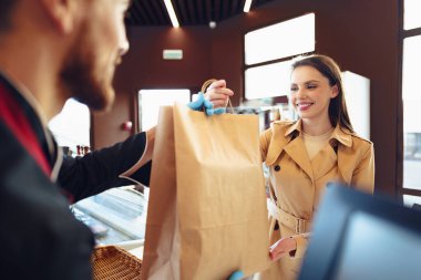 Markette alışveriş çantasıyla ilgilenen tezgahtar.