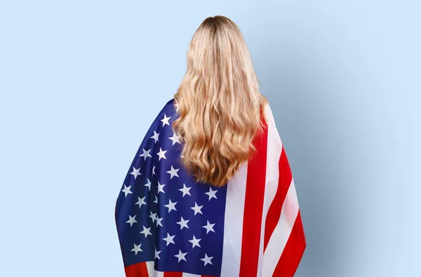 Portret młodej kobiety trzymającej flagę USA na tle koloru — Zdjęcie stockowe