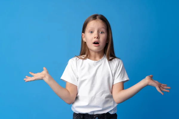 Menina chocada olhando com espanto no fundo azul — Fotografia de Stock