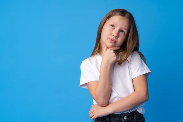 Menina pensando e olhando para cima sobre fundo azul — Fotografia de Stock