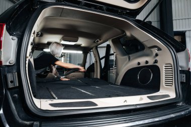 İşçi kadın, araba yıkamada arabanın içindeki tozları temizliyor..