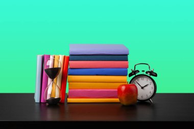 Siyah ahşap masada yığınla kitap.