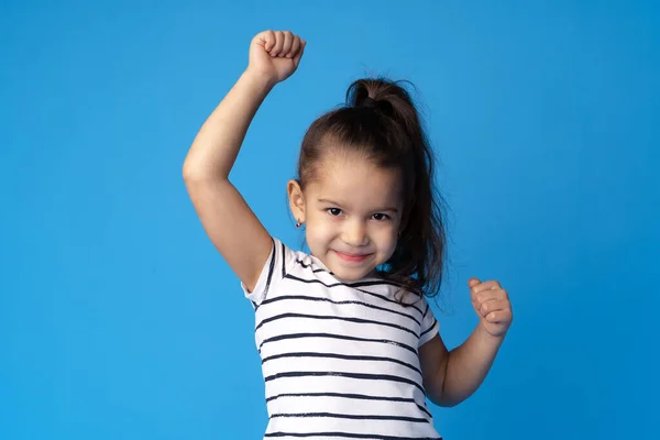Kicsi aranyos lány mutatja erejét a kék háttér — Stock Fotó