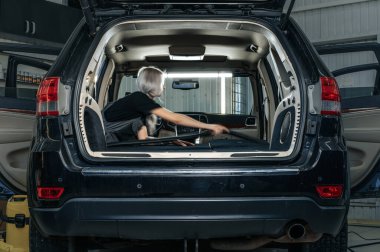 İşçi kadın, araba yıkamada arabanın içindeki tozları temizliyor..