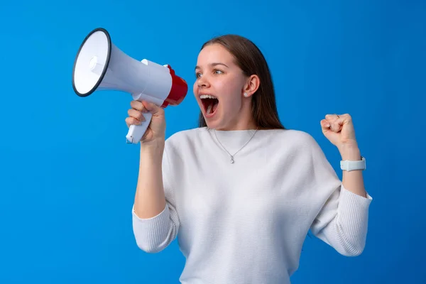 Adolescente fazendo anúncio com megafone no estúdio azul — Fotografia de Stock