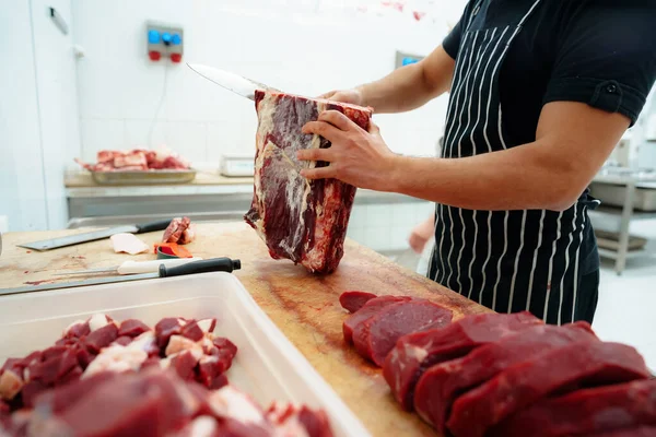 Close-up de mãos masculinas cortando carne crua na placa de corte de madeira — Fotografia de Stock