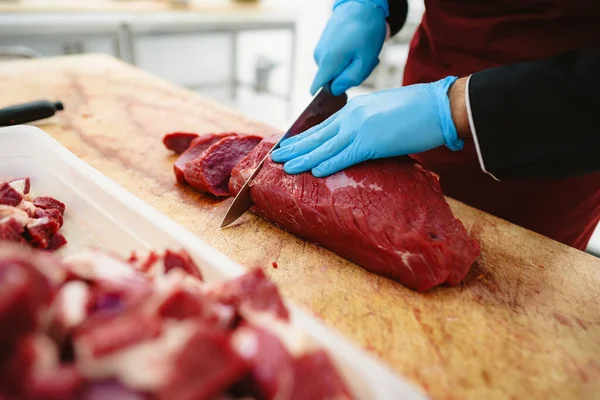 Butcher cutting slices of raw meat on wooden board — Stock Photo, Image