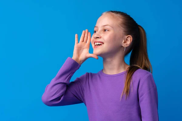 Kislány sikoltozik valamit a kék háttér — Stock Fotó