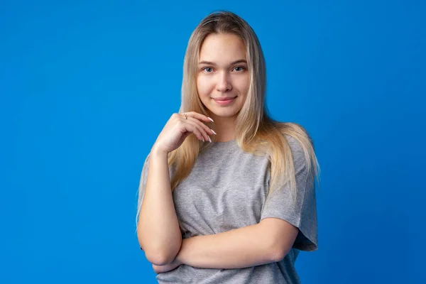 Портрет симпатичной улыбающейся девушки на голубом фоне в студии — стоковое фото