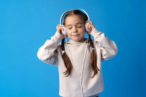 Niña niña usar auriculares escuchar música sobre fondo azul — Foto de Stock