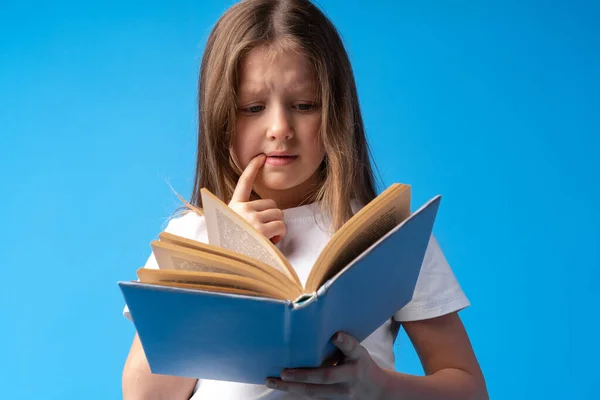 Little piękne uśmiechnięta dziewczyna gospodarstwa książki na niebieskim tle — Zdjęcie stockowe