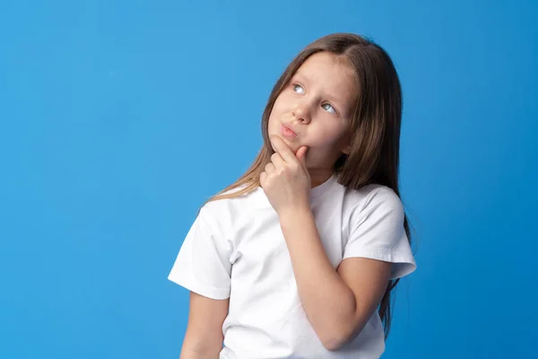 Kislány gondolkodás és felnézett a kék háttér — Stock Fotó