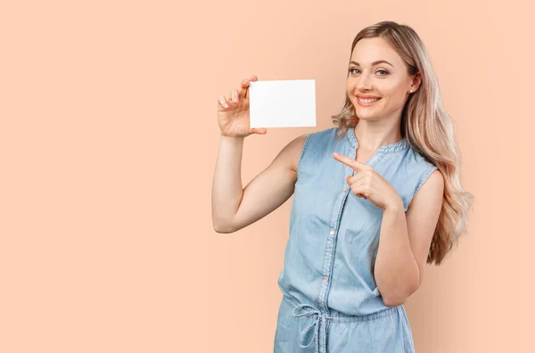 Feliz hermosa mujer casual sosteniendo una tarjeta en blanco aislado en el fondo de color — Foto de Stock