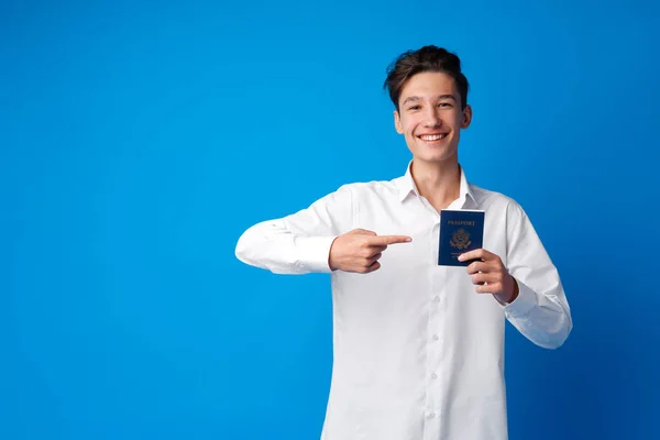 Portret przystojnego chłopca pokazującego paszport na wakacjach na niebieskim tle — Zdjęcie stockowe