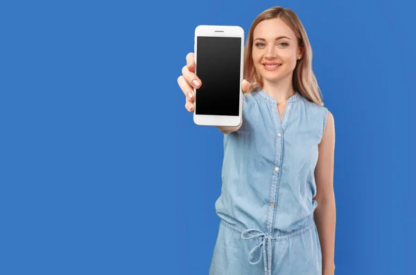 Portré egy mosolygós nő mutatja üres okostelefon képernyő elszigetelt egy színes háttér — Stock Fotó