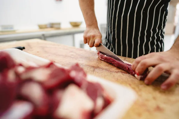 Carnicero cortando rebanadas de carne cruda en tablero de madera — Foto de Stock