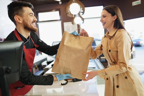 食料品店の女性顧客へのショッピングバッグを扱うショップアシスタント — ストック写真