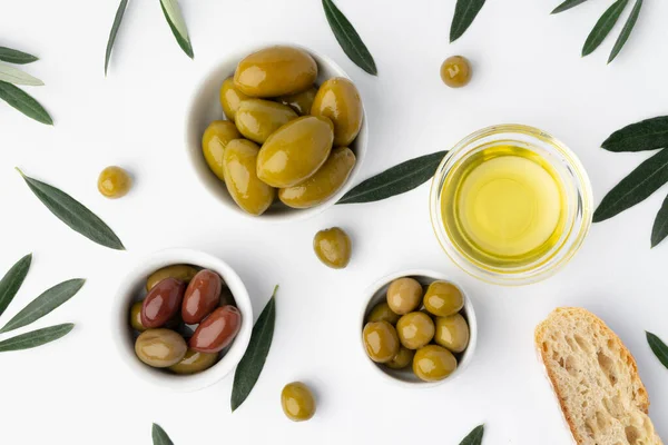 Маленька миска з оливковою олією та оливками на білому тлі, вид зверху — стокове фото