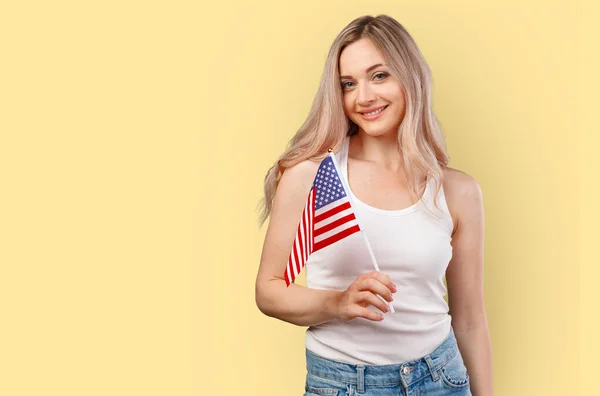 Portrait d'une jeune femme tenant le drapeau américain isolé sur fond de couleur — Photo