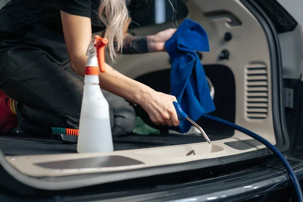 Жінка прибирає автосалон з полірувальним спреєм в автосервісі — стокове фото