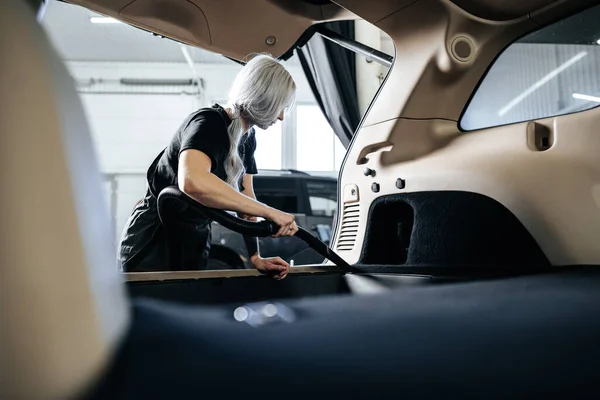 Εργαζόμενη γυναίκα κενό καθαρισμού σκόνη εσωτερικό αυτοκίνητο στο πλυντήριο αυτοκινήτων. — Φωτογραφία Αρχείου