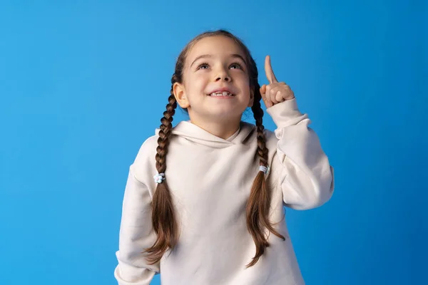Aranyos kislány rámutatott, és van egy ötlete a kék háttér — Stock Fotó