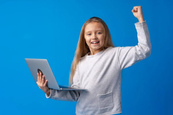 Retrato de uma menina segurando computador portátil enquanto estava contra o fundo azul — Fotografia de Stock