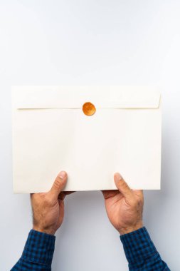 Erkek eller, içinde balmumu mühür olan bir zarf tutuyor.