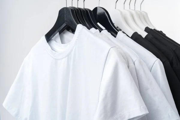 Black and white T-shirts on hangers on metal rack isolated on white — Stock Photo, Image