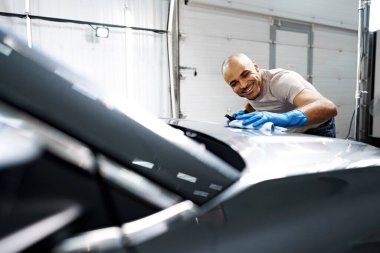 Bir arabaya nano kaplama uygulayan Afro-Amerikan araba servisi çalışanı.