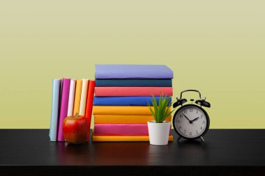 Siyah ahşap masada yığınla kitap.