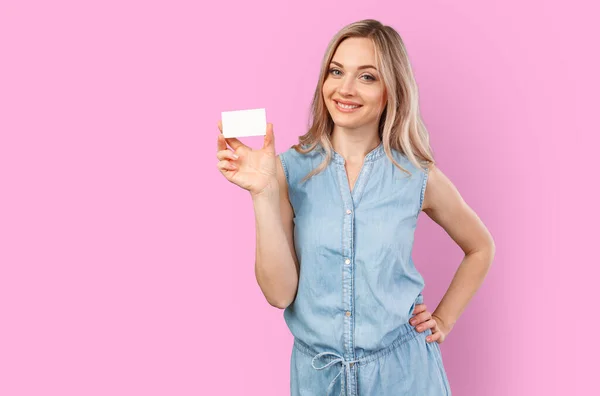 Happy beautiful casual woman holding a blank card isolated on color background — Stock Photo, Image