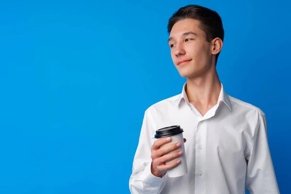 Adolescente menino beber uma xícara de café sobre fundo azul — Fotografia de Stock